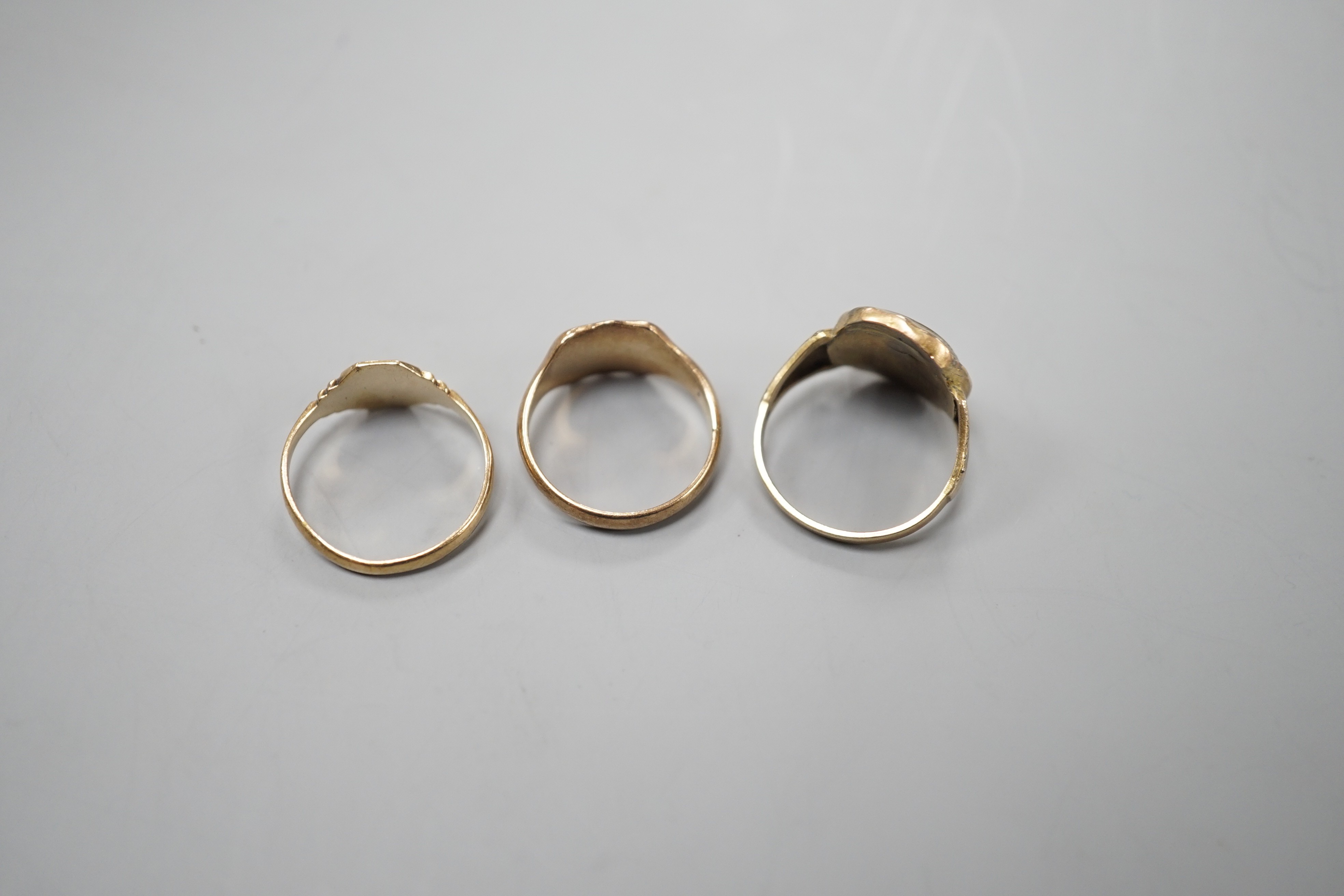 A 19th century yellow metal mourning ring, with plaited hair beneath a glazed panel size L, together with two later 9ct gold signet rings, gross weight 6.3 grams.